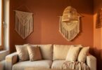 Salon chaleureux avec mur terracotta, coussins en lin beige, suspension en rotin et décoration macramé murale