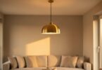 Suspension design en laiton dans un salon moderne aux murs neutres, lumière chaleureuse de fin d après-midi