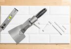 Carreaux de crédence, spatule crantée et croisillons prêts pour poser du carrelage mural soi-même