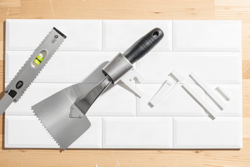 Carreaux de crédence, spatule crantée et croisillons prêts pour poser du carrelage mural soi-même