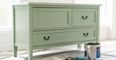 Meuble en bois en cours de peinture avec pinceau, rouleau et pot de peinture